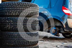 Winter tires next to the car in wheel service, seasonal tire change concept, close-up