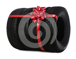 Winter tires with red ribbon on white background