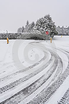 Winter tires traces on snowy road turn with stop sign in front