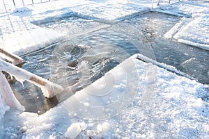 Winter tradition. The man plunged headlong into cold water into a hole-cross on the river. Wooden railing covered with ice.