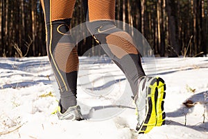 Winter trail running: man takes a run on a snowy mountain path in a pine woods.