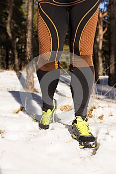 Winter trail running: man takes a run on a snowy mountain path in a pine woods.