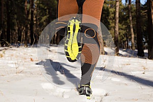 Winter trail running: man takes a run on a snowy mountain path in a pine woods.