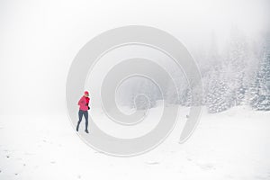 Winter trail running on snow in white forest and mountains