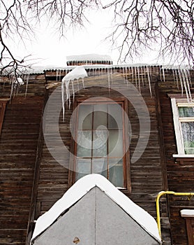 Winter transparent icicles hang on the edge of the roof.