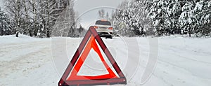Winter transport and vehicle concept closeup of red warning triangle with broken car
