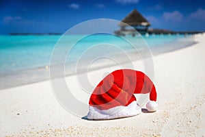 Winter travel concept with a christmas santa hat on a tropical beach
