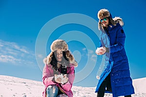 Winter, two girls having fun in the snow in the mountains