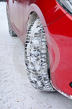 Winter tyre, red car, empty snowy road