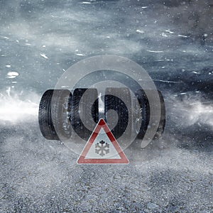 Winter tyres with snow for season with a warning sign