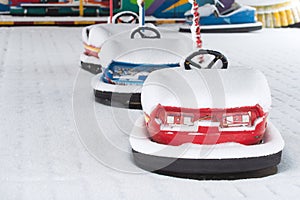 Winter urban scene. Dodgem cars or electric bumper cars after snowfall