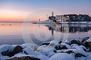 Winter in Urk with the dike and beach by the lighthouse of Urk snow covered during winter, sunset by the lighthouse of photo