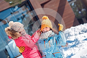 Winter vacation. Family time together outdoors daughter playing with mother taking off her hat laughing cheerful close
