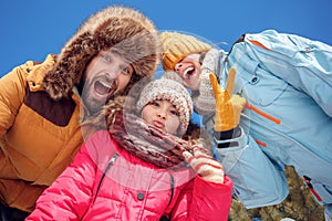 Winter vacation. Family time together outdoors grimacing to camera laughing playful bottom view close-up