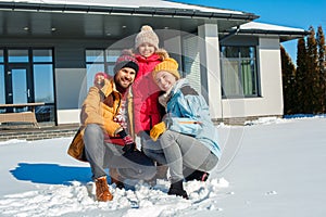 Winter vacation. Family time together outdoors standing near house hugging smiling cheerful