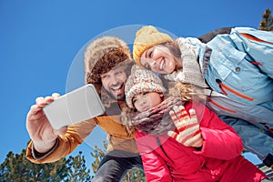 Winter vacation. Family time together outdoors taking selfie on smartphone smiling cheerful bottom view