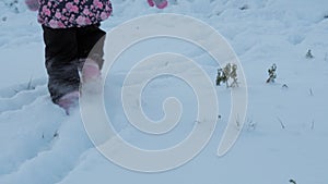 Winter, vacation, game, family concept - slow motion close up baby walk through deep snow. children feet tread on snowy