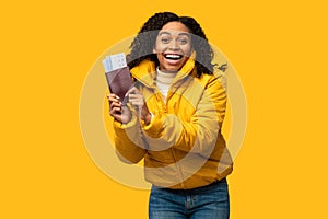 Black Girl Showing Tickets Going On Winter Vacation, Yellow Background