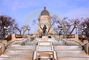 Winter view from the bank of Assiniboine River on Manitoba Legislature building with Louis Riel sculpture in Winnipeg