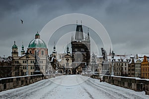 Winter view of Charles bridge, Old Town bridge tower covered with snow, Prague, Czech Republic. People walking through the city in