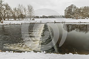 Winter view for Malse river and weir in snowy cold cloudy day