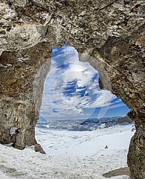 Winter views of the fascinating mountain range from the entrance of a cave in the peak mountains