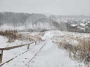 Winter village landscape. Old wooden staircase was covered with snow