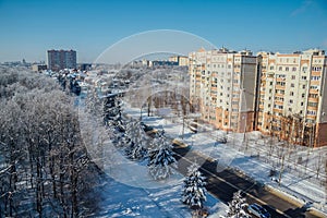 Winter Voronezh cityscape. Frozen trees in a forest covered by snow and hoarfrost near modern houses in the city of Voronezh