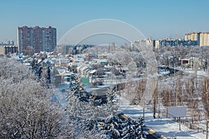 Winter Voronezh cityscape. Frozen trees in a forest covered by snow and hoarfrost near modern houses in the city of Voronezh