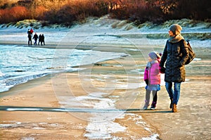 Winter walk by Baltic sea, mother and daughter