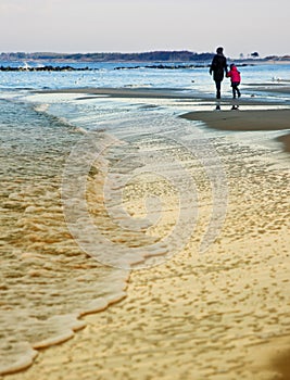 Winter walk by Baltic sea, mother and daughter