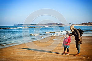 Winter walk by Baltic sea, mother and daughter