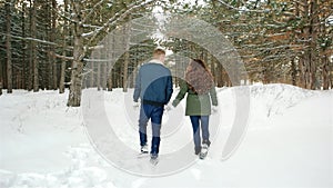 Winter walk, Beautiful guy and the girl go on a snowy road through the trees, the happy couple in love