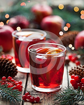 Winter warm drink. Cranberry orange pomegranate punch or mulled wine, sangria wooden table. Christmas tree decorations.