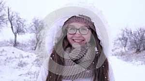Winter weather, elated woman into glasses standing under falling snow in open air