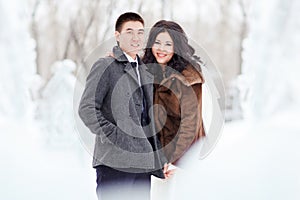 Winter wedding, the bride with veil, groom in wintry clothes on the street in the middle of ice figures and snow