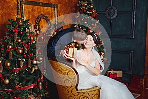 Winter Wedding .Lovers bride and groom in christmas decoration . Groom holding Gift . romantic surprise for Christmas