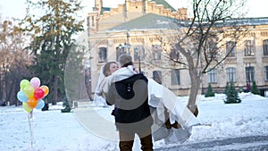 Winter wedding. newlywed couple in wedding dresses. groom holds bride in his arms, spinning. they are happy, smiling to