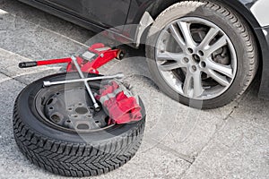 Winter wheel lying near car on summer tires