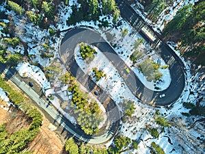 Winter winding road in the mountains with cars passing through