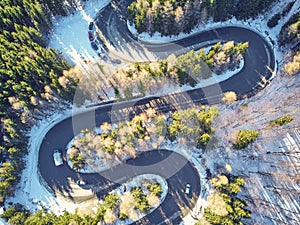 Winter winding road in the mountains with cars passing through