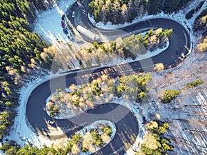 Winter winding road in the mountains with cars passing through