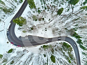 Winter winding road in the mountains with cars on the road