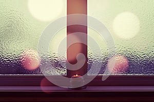 Winter window with burning candle and bokeh lights