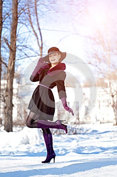 Winter woman on background of winter landscape, sun. Fashion girl in forest wonderland. Winter sunset scene. Model in sunlight, b