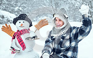 Winter woman. Cute girl making snowman on snowy field outdoor. Joyful Beauty young woman Having Fun in Winter Park.