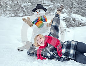 Winter woman. Greeting snowman. Snowman and funny female model standing in winter hat and scarf with red nose. Cute