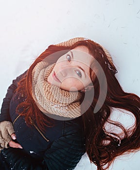 Winter. Woman with red hair wearing ear muffs looking at the camera