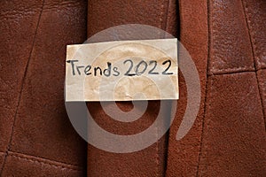winter women's brown sheepskin coat as a background, natural winter coat and text on a piece of paper trends 2022