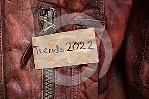 winter women's brown sheepskin coat as a background, natural winter coat and text on a piece of paper trends 2022